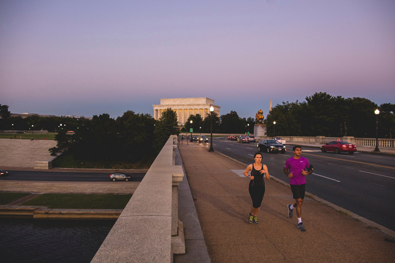 Couple running by the Lincoln Memorial in warm weather - Outdoor activities and fitness in Washington, DC